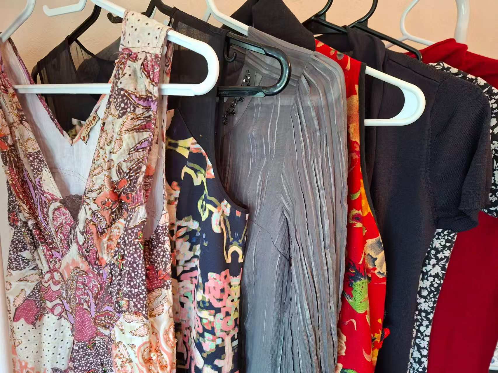 A selection of patterned and solid-colour clothing on hangers